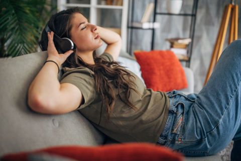 Woman enjoying music on couch with headphones